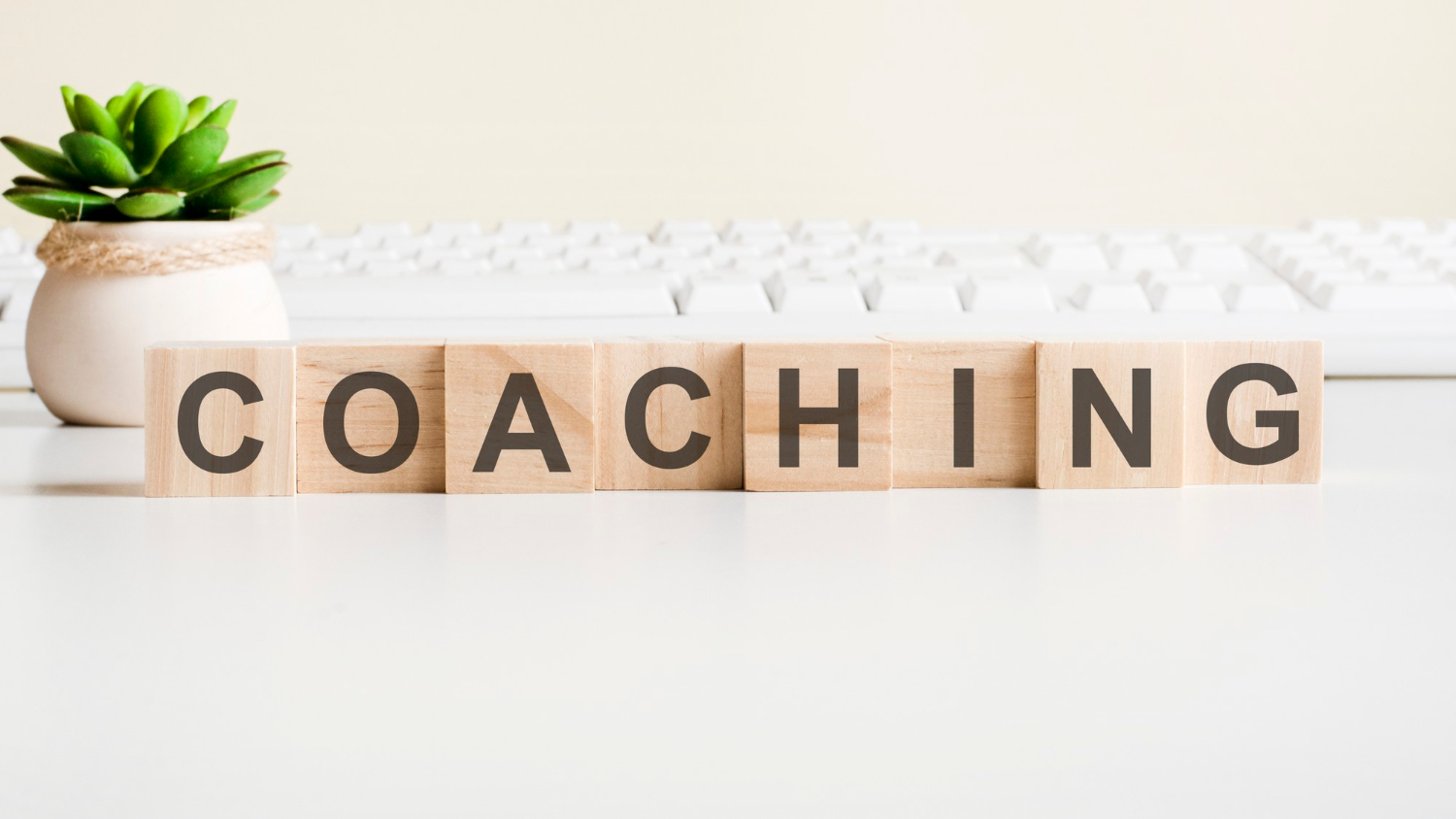 Le mot coaching fait avec des blocs de bois posés devant un clavier d'ordinateur. 